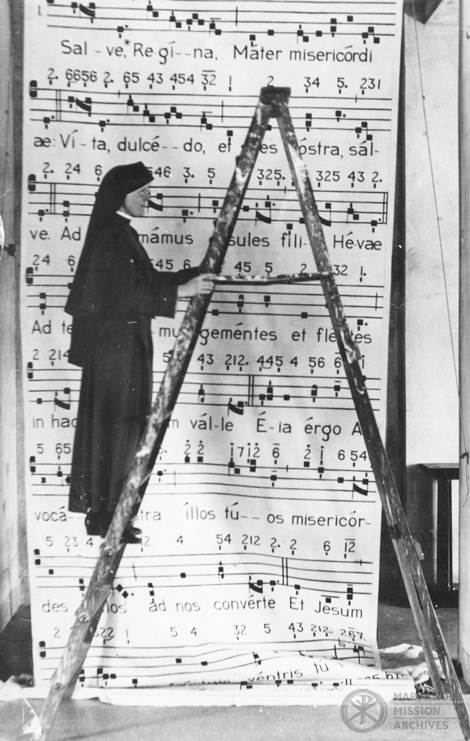 Sr. Kathleen Ryan hanging a sheet music poster