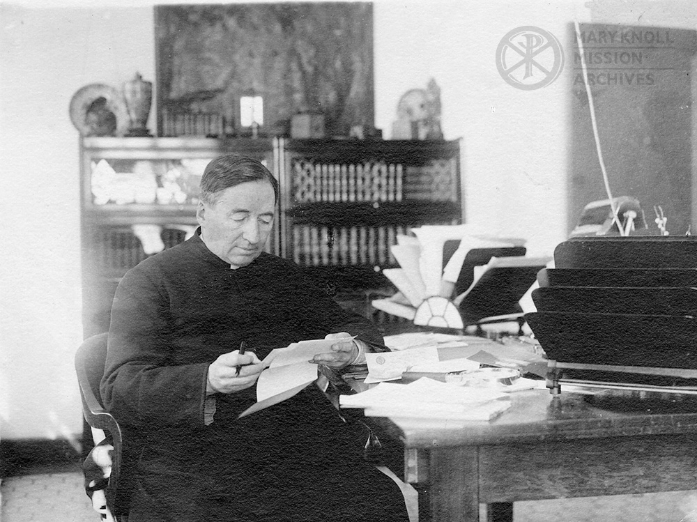 Bishop James A. Walsh at desk holding his pen and reading a letter