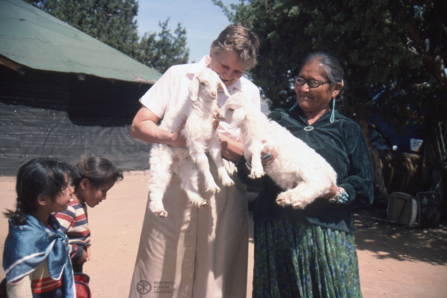 Sr. Lorriane Carney holds a white baby goat while visiting a Navajo family, Navajo Reservation Gallup, New Mexico, 1984